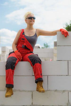 Woman in dungarees relaxing after hard work on construction site. Young female lying outdoor taking a breakの写真素材