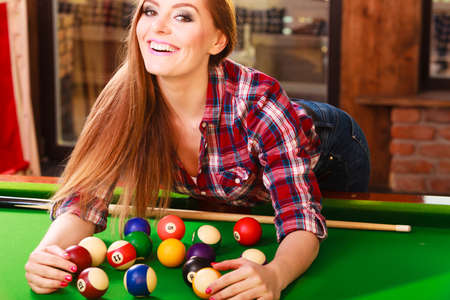 Fashion and fun concept. Young charming girl posing by billiard pool. Attractive fashionable woman...