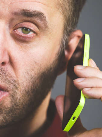 Suspicious man close up, adult guy using phone talking on smartphone with somebody.