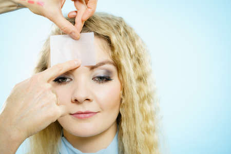 Professional artist fixing fashion model make up using oil blotting tissues. Cosmetic objects,...