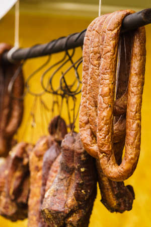 Traditional food. Smoked sausages ham meat hanging in domestic smokehouse on strings.の写真素材