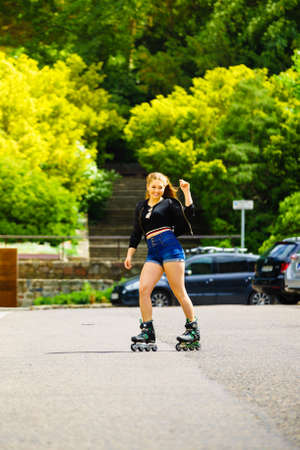 Teenage woman girl riding roller skates during summertime through city having great time.の写真素材