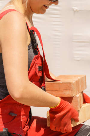 Strong pretty woman working on construction site, building house, installing bricks. Industrial work...