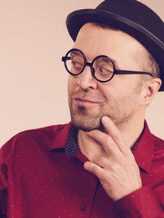 Funny guy wearing eyeglasses and fedora hat. Adult man having weird outfit gesturing with hands.