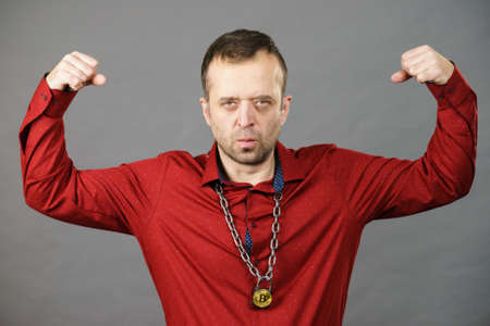 Adult man having necklace made of chain with bitcoin cryptocurrency symbol. Guy being addicted to...