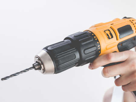 Unrecognizable woman holding yellow driller about to drill something. Hardware construction site...