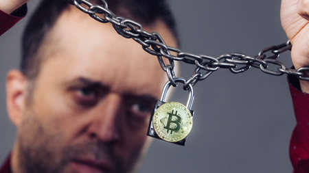 Man having problems with crypto currency. Adult guy being tied up with block chain bitcoin.
