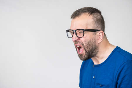 Adult man wearing eyeglasses yelling at somebody. Side profile view with copy spaceの写真素材