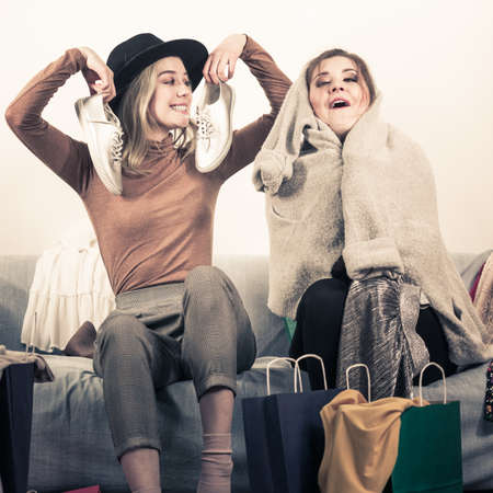 Two happy joyful women having fun after shopping, picking outfit in closet. Female friends fooling around.の写真素材