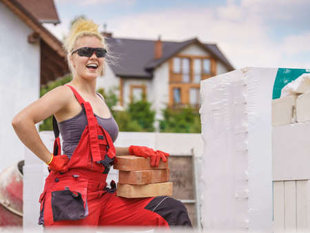 Strong pretty woman working on construction site, building house, installing bricks. Industrial work concept.の写真素材