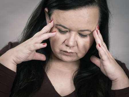Headache, migraine and stress. Worried plus size adult upset woman suffering from head pain, studio...