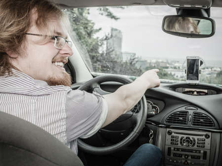 Young student, ginger man behind steering wheel. Happy cheerful guy driving a car.の写真素材