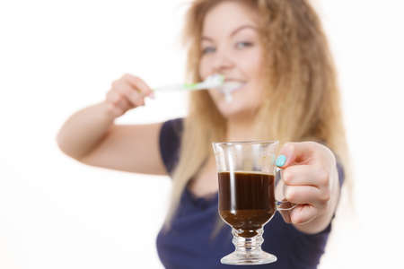 Happy woman holding toothbrush and coffee going to brush her teeth after hot drink. Discoloration...