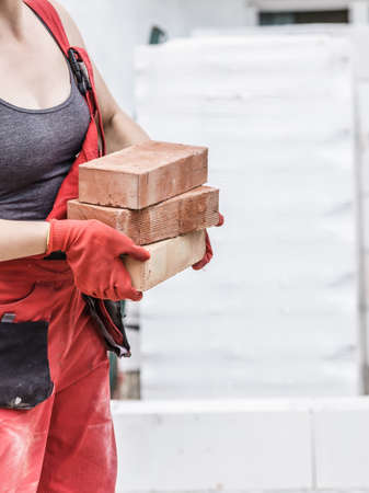 Strong woman working on construction site, building house, installing bricks. Industrial work concept.の写真素材