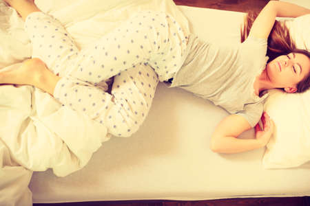Mornings people concept. Sleepy woman sleeping in the bed. Attractive lady changing sleep positions.