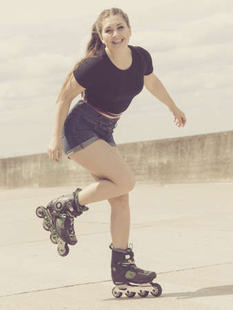 Happy joyful young woman wearing roller skates relaxing after long ride. Female being sporty having fun during summer time on pierの写真素材