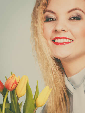 International women day, eight march. Beautiful portrait of pretty woman blonde hair with red yellow tulips, fashion make up. Mother day. Toned imageの写真素材