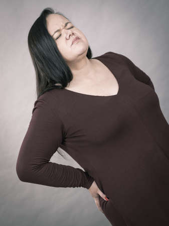 Plus size adult woman having health problem suffering with loins pain kidney ache.