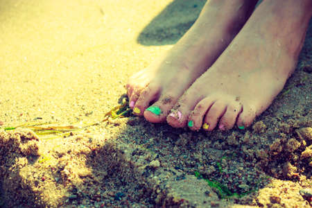 Well cared women feet with colorful nail polish on beach