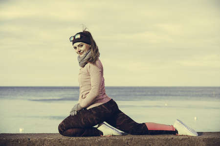 Woman athlete girl training wearing warm sporty clothes outside by seaside in cold weather. Sports...
