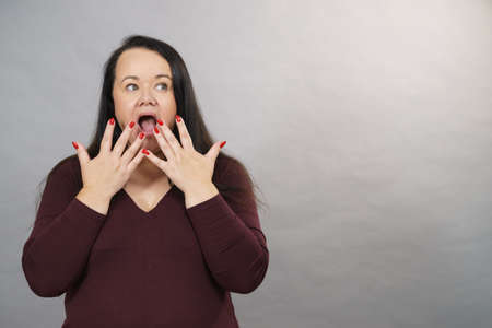 Shocked surprised mature adult woman gesturing with hands being terrified or scared.