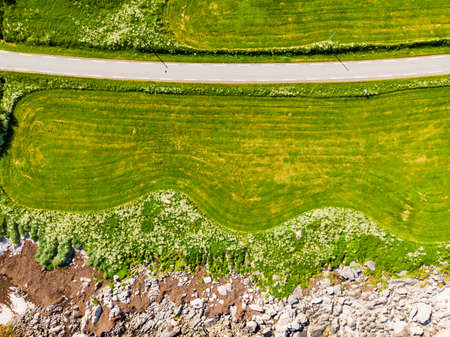 Aerial top down view of country road through green land field along sand beach seashore, Gimsoya...
