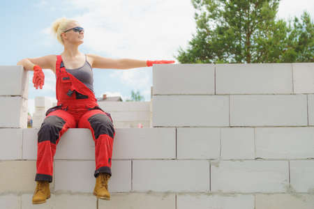 Woman in dungarees relaxing after hard work on construction site. Young female lying outdoor taking a breakの写真素材