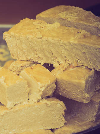Slices of brown Halva with peanut and walnut on a silver plate.