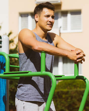 Handsome guy relaxing after outdoor workout. Fit happy man feeling healthy enjoying sun