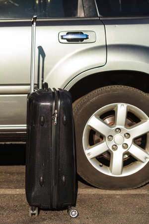 Cropped view of black suitcase at car. Business trip.の写真素材