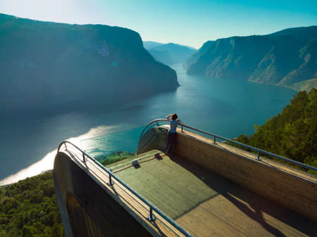 Tourist woman enjoying fjord view Aurlandsfjord landscape from Stegastein viewing point. Norway...