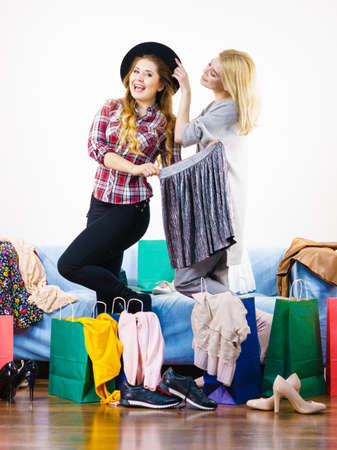 Two happy joyful women having fun after shopping, picking outfit in closet. Female friends fooling around.の写真素材