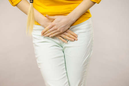 Closeup young sick woman with hands holding pressing her crotch lower abdomen. Medical or...