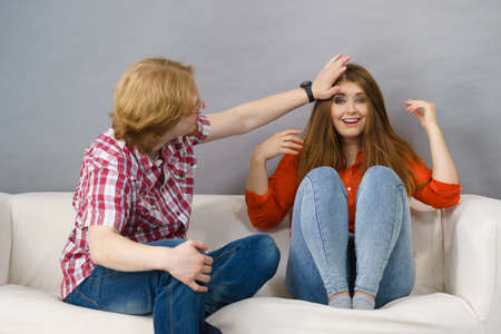 Happy male and female two friends sitting on sofa chatting and having funの写真素材