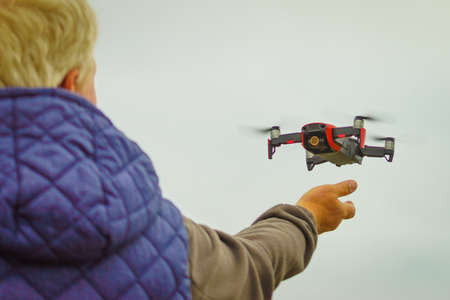 Start the drone, launching from hands. Modern small copter with camera in user hand, against sky....