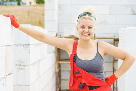 Happy woman working on construction site. Partially built new home early stage. Industry.の写真素材