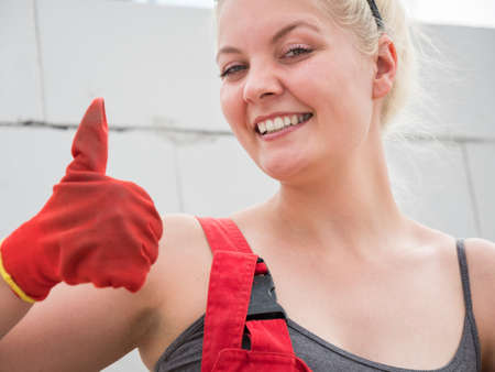 Happy woman wearing workwear working on construction site. Female making ok sign gesture as good...