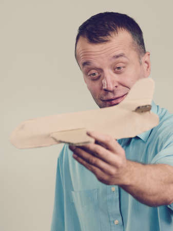 Fly fear metaphor, aerophobia concept. Business man holding airplane in hand, fear face expression,...