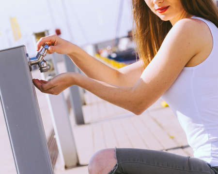 Woman drinking clean water from tap in marina.