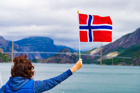 Female tourist with norwegian flag enjoying fjord Lysefjord view. National route Ryfylke. Vacation and travel.の写真素材