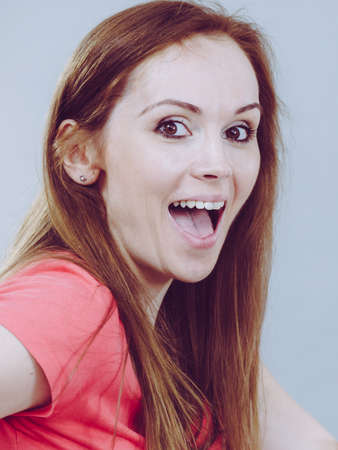 Funny happy young adult woman having excited face expression with mouth wide open. Close up portrait.の写真素材