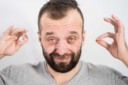 Man about to clean his ears using Q-tip cotton swab. Hygiene essentials concept. Removing wax from ear.の写真素材