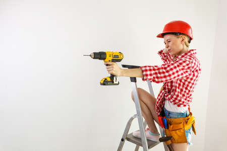 Woman having troubles with using construction drill. Female does not know how to use driller.の写真素材