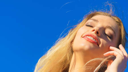 Close up of beautiful young woman face in sunlight. Blonde female enjoying vacations and sunshine.の写真素材