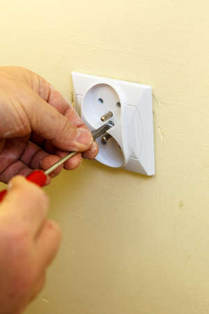 Person adjusting, removing electric power socket plug. Fixing, installing electricity, electrician services concept.の写真素材