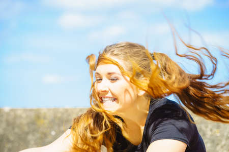 Happy teen woman enjoying her leisure time. Female having long brown hair posing with sky in backgroundの写真素材
