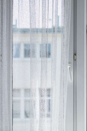 Young adult man spying at his neighbors, guy using binoculars looking through window.