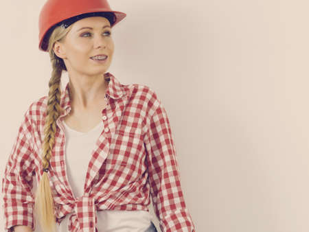 Happy joyful woman wearing helmet and checked shirt being positive about construction work.の写真素材