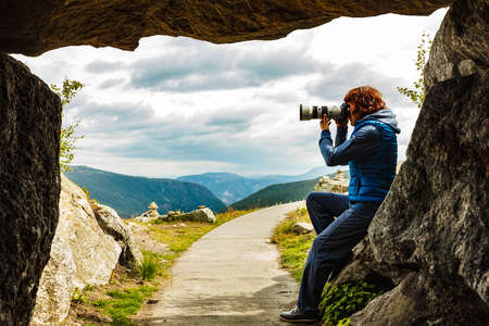 Woman with camera on Vedahaugane viewpoint at entrance to underground cave. National Tourist Route Aurlandsfjellet.の写真素材