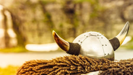 Equipment of viking or barbarian warrior outdoor on nature. Viking helmet on brown fur of animal in Norway. Tourism and traveling conceptの写真素材